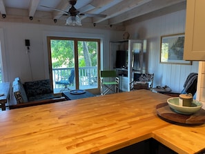 A wooden interior with a kitchen area, a dining table, and a seating area with a view of the outdoors.