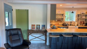 Una cocina moderna con barra, una silla de comedor y una puerta verde.