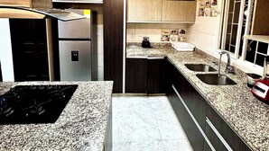 Eine moderne Küche mit einer zentralen Kochinsel, Edelstahlgeräten und einem eingebauten Backofen.