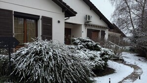 Un edificio residencial con un sendero cubierto de nieve y un arbusto al frente.