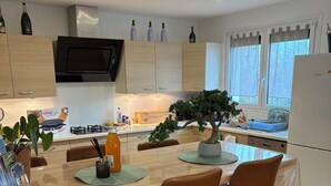 Una cocina moderna con comedor, que incluye una isla central, taburetes de bar, un bonsái y un refrigerador Bosch.