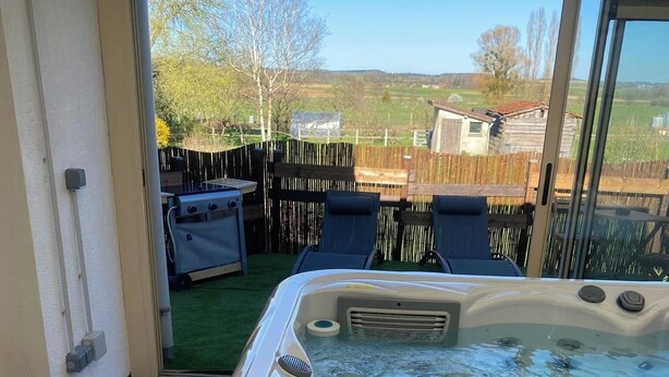 Un jacuzzi con vista a un patio trasero, una terraza de madera y una valla.