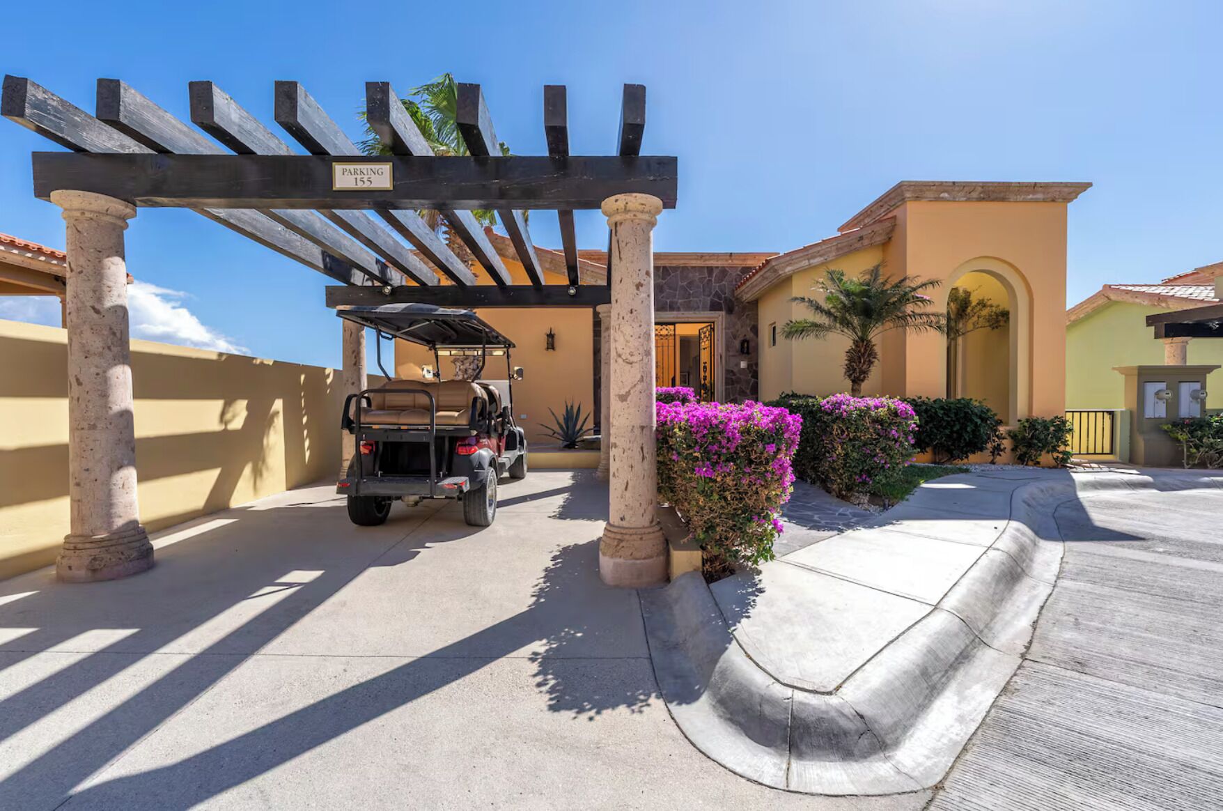 A gated entrance with a golf cart, a pergola, and a building with a stone facade.
