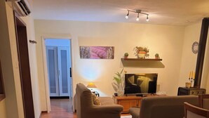 Ein Wohnzimmer mit einer Couch, einem Fernseher, einem Couchtisch und einer Zierpflanze.