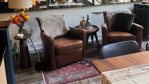 A cozy living area with leather armchairs, a coffee table, a patterned rug, and a staircase with a view of a bookshelf and plants. - Cozy 1-bedroom condo in Atlanta walking distance to Mercedes Benz Stadium (Atlanta)