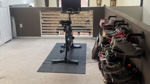 A room with a ceiling fan, a treadmill, a window with a view, a wall-mounted shoe rack, and a brick wall. - Cozy 1-bedroom condo in Atlanta walking distance to Mercedes Benz Stadium (Atlanta)