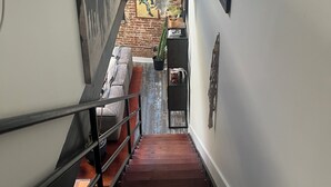A staircase leading to a lower level with a brick wall, a potted plant, and a framed picture on the wall. - Cozy 1-bedroom condo in Atlanta walking distance to Mercedes Benz Stadium (Atlanta)