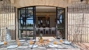 An outdoor dining area with a table set for four, a pineapple centerpiece, and orange juice glasses. - Wine estate | 20m pool and cinema (Pézenas)
