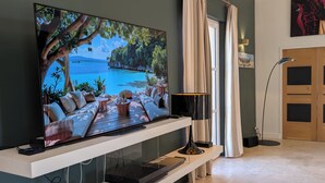 Moderni olohuone, jossa on litteänäyttöinen televisio, sohva, sohvapöytä ja lamppu.