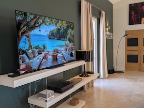 Una sala de estar moderna con un televisor de pantalla plana, un sofá, una mesa de centro y una lámpara.