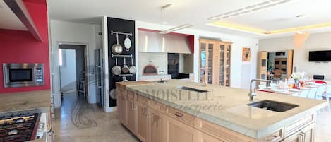 A modern kitchen with a central island, stainless steel appliances, and a red accent wall.