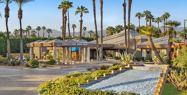Et hotel med et ørkeninspireret udseende, palmer og et skilt, der viser 'Marriott’s Desert Springs Villas'.