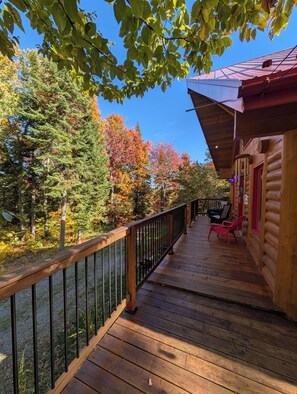 Eine Holzhütte mit einer Terrasse, umgeben von Bäumen im Herbstlaub.