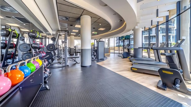 Een moderne sportschool met loopbanden, krachtapparaten en kleurrijke kettlebells.