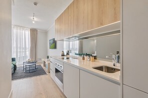 Eine moderne Küche mit einer großen Kochinsel, Edelstahlgeräten und Blick zum Wohnbereich.