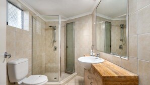 A bathroom with a toilet, sink, mirror, shower, and glass-enclosed shower stall. - 2 Bedroom Courtyard Poolside (Kings Beach)