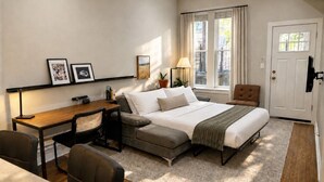 A bedroom with a bed, a desk, a chair, a sofa, a lamp, and a door. - Flexhome West Town Spacious 2BR Duplex · Sleeps 8 (Chicago)