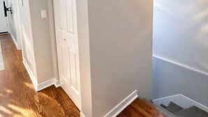 A hallway with wooden flooring, white walls, and a door. - Flexhome West Town Spacious 2BR Duplex · Sleeps 8 (Chicago)