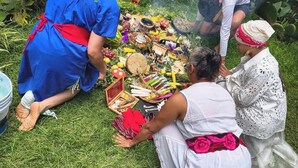 Un groupe de personnes s’est rassemblé autour d’une installation préparée pour une cérémonie, en plein air.