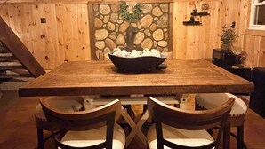 Ett matrum med träpanel, en vägg av sten, en öppen spis och en trappa.