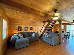 Ein Holzinnenraum mit zwei grauen Sofas, einer Treppe und einem Essbereich.