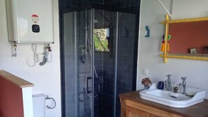 A bathroom with a glass shower enclosure, a toilet, a sink, and a wooden cabinet. - Dependent room at the bottom of the garden (Perros-Guirec)