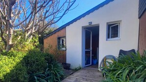 A wooden pathway leading to a modern building with a door and windows. - Dependent room at the bottom of the garden (Perros-Guirec)