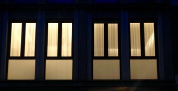 Facciata di un edificio con numerose finestre, ciascuna con una tenda.