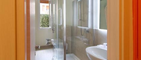 A bathroom with a glass-enclosed shower, a sink, and a mirror.