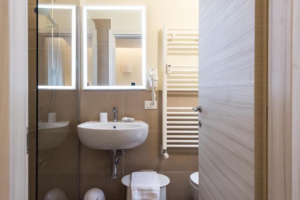A bathroom with a glass shower enclosure, a sink, a toilet, and a towel rack.
