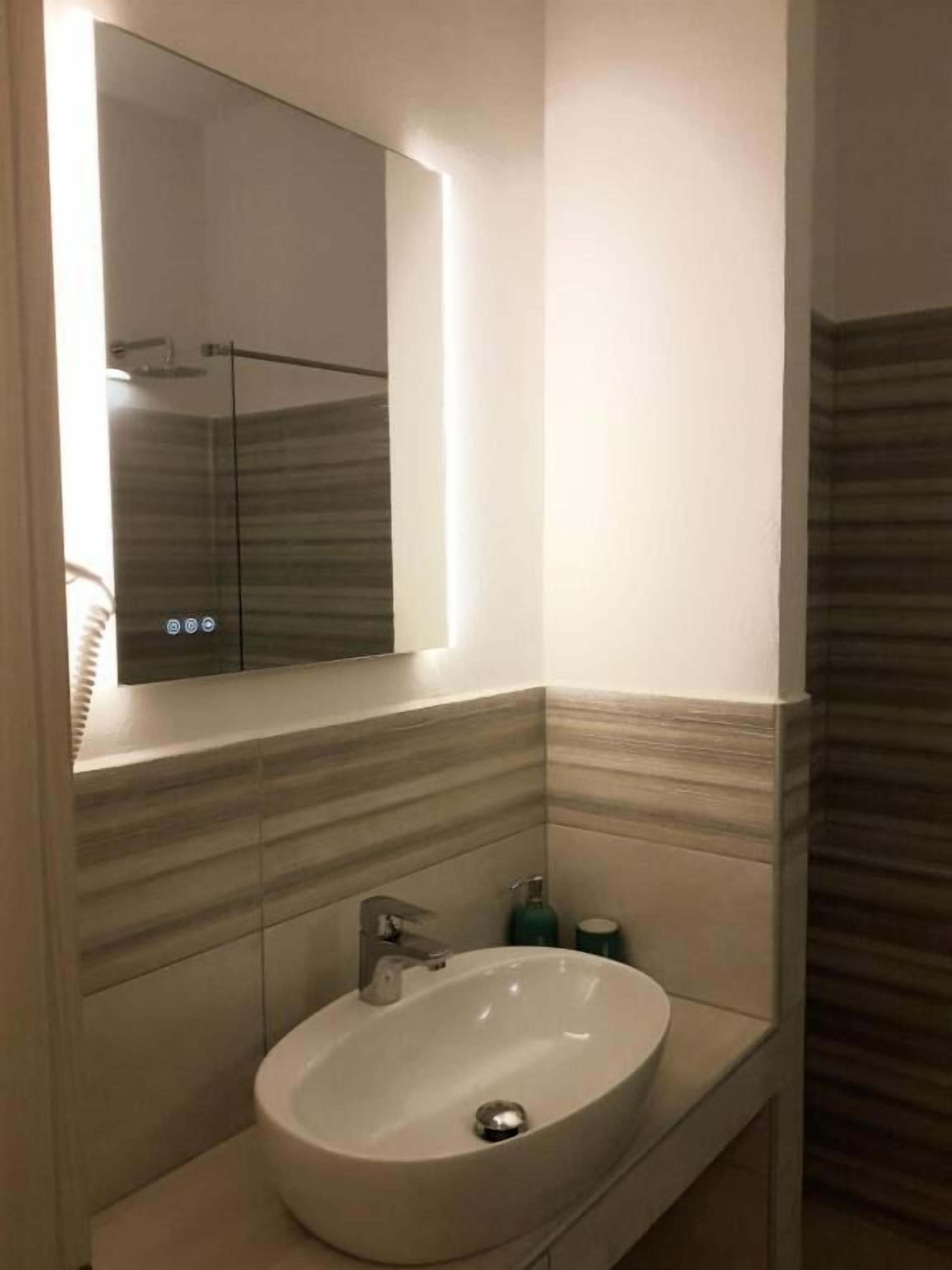 A bathroom with a white sink, a mirror, and a shower.