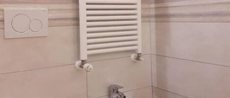 A bathroom with a toilet, bidet, and a towel rack.