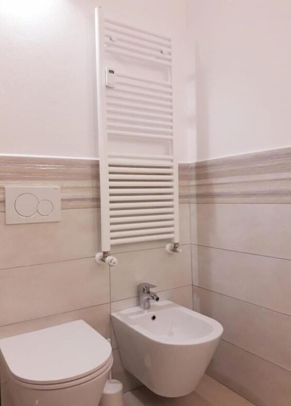 Ein Badezimmer mit Toilette, Bidet und Handtuchhalter.