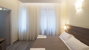 A hotel room with a bed, a nightstand, a lamp, and a window with curtains. - San Felice 135 - 4 (Bologna)