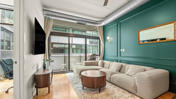 A modern living room with a sectional sofa, a round coffee table, and a flat-screen TV mounted on the wall. - Luxury Fulton Market Condo - Prime Location
Walking distance to Riverwalk (Chicago)