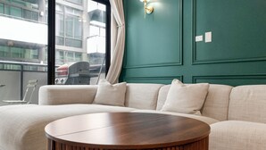 A modern living room with a sectional sofa, a round wooden coffee table, and a view of a cityscape through large windows. - Luxury Fulton Market Condo - Prime Location
Walking distance to Riverwalk (Chicago)
