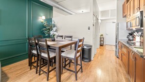 A modern kitchen with wooden cabinets, a stainless steel refrigerator, and a dining area with a wooden table and chairs. - Luxury Fulton Market Condo - Prime Location
Walking distance to Riverwalk (Chicago)