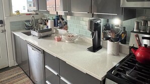 Eine moderne Küche mit grauen Schränken, Edelstahlgeräten und einem roten Wasserkocher.