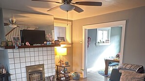 Ein Wohnzimmer mit Kamin, Deckenventilator, Sofa und Fernseher.