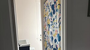 Ein Badezimmer mit Toilette, Waschbecken, einer Duschkabine mit Blumenmuster und einem Teppich.