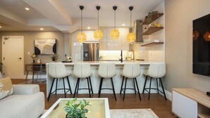 Een moderne keuken met een centraal kookeiland, hanglampen en barstoelen.