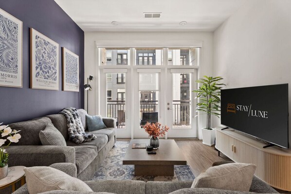 Una sala de estar moderna con un sofá gris, una mesa de centro y un televisor de pantalla plana.