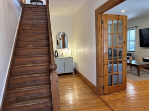 Eine Holztreppe führt zu einem Raum mit einem grauen Schrank, einem Spiegel und einer Holztür.