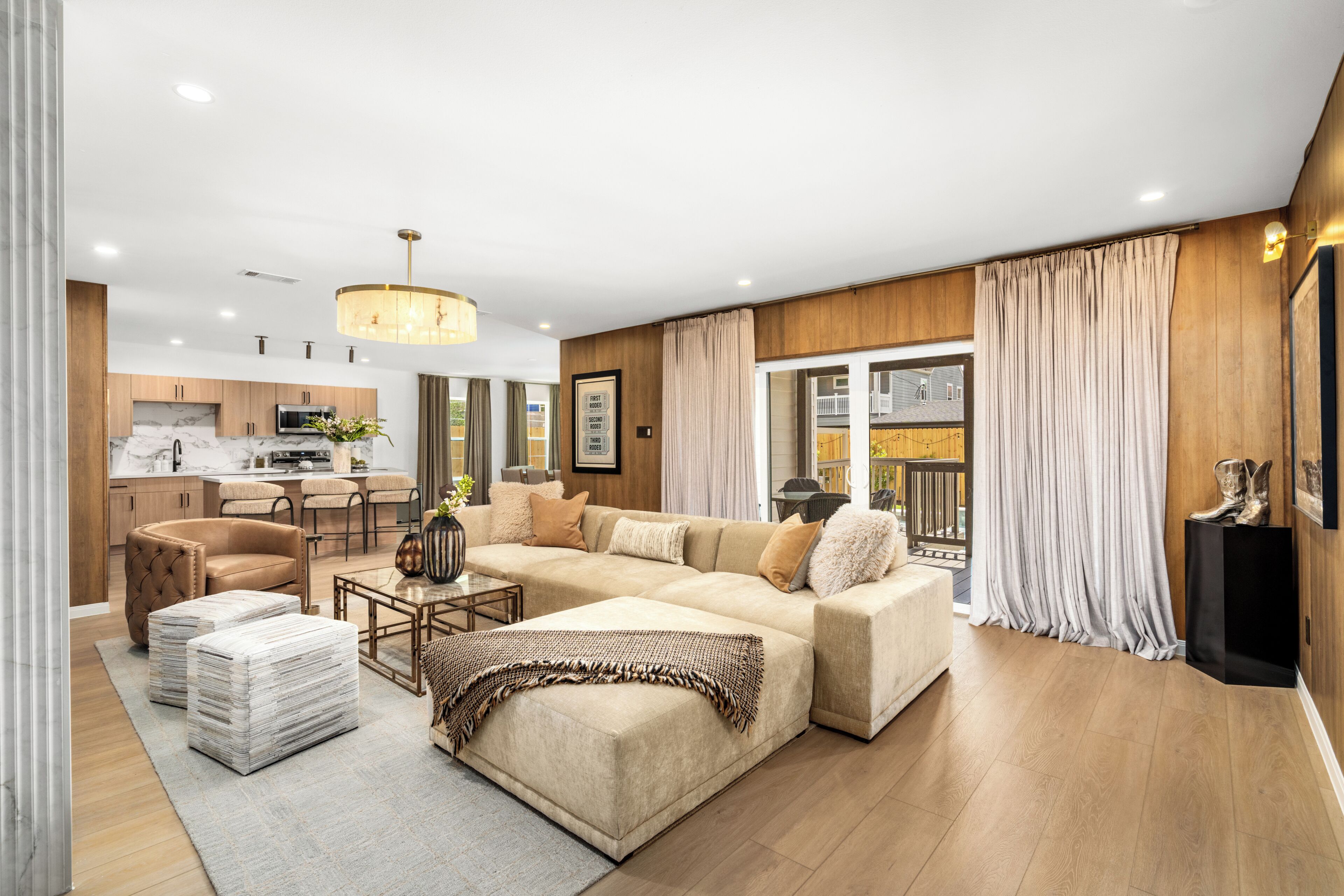 A modern living room with a sofa, ottomans, and a dining area with chairs and a table.