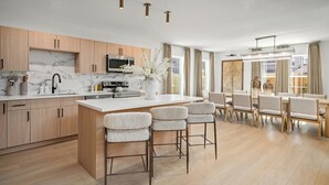 A modern kitchen with marble countertops, wooden cabinets, and a central island with bar stools.