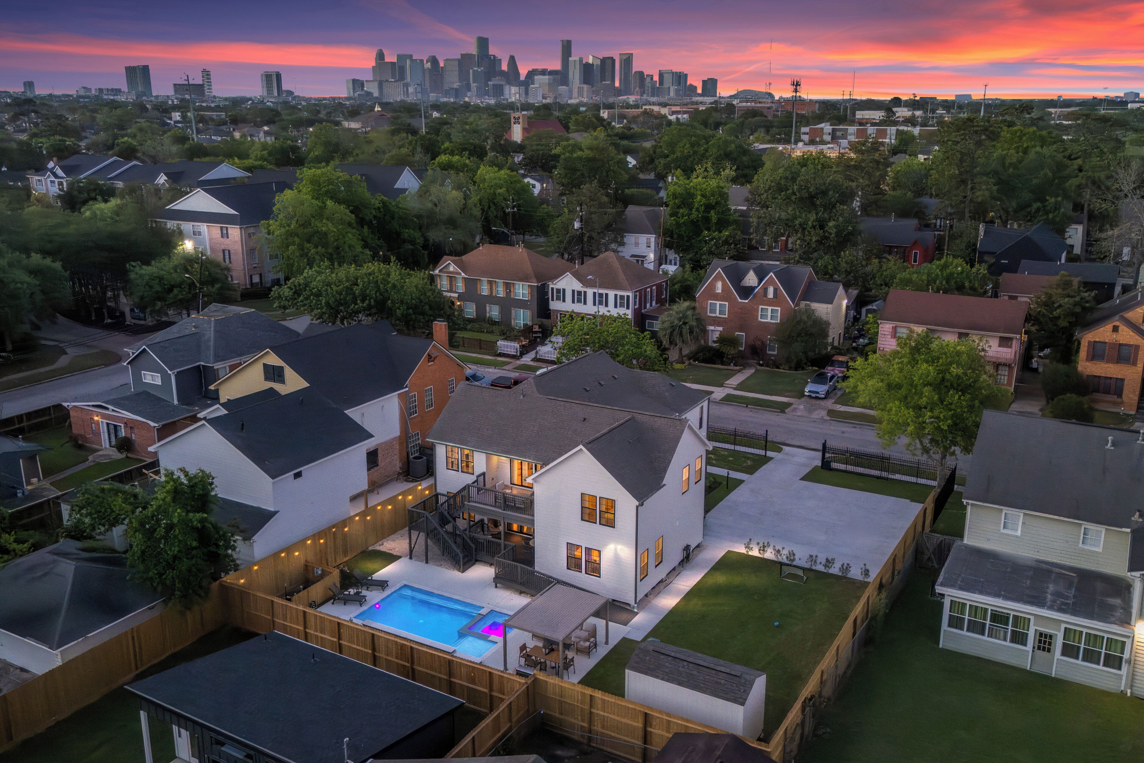 Un quartier résidentiel avec des maisons, une piscine et, en arrière-plan, la silhouette de la ville.