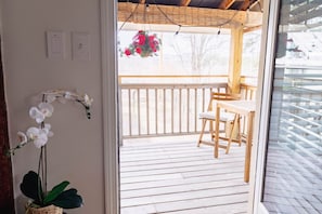 Une terrasse en bois avec une rambarde, une jardinière suspendue et une chaise.