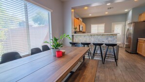 A modern kitchen with a wooden table, bar stools, and a potted plant. - 3-bedroom 2 bath 1 office fully furnished Florence House (Florence)