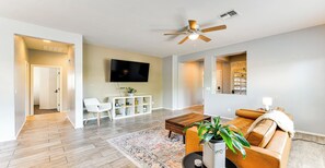Ein Wohnzimmer mit Fernseher, Sofa, Couchtisch und Deckenventilator.