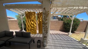 An outdoor patio with a covered seating area, a pergola, and a view of a brick wall and greenery. - 3-bedroom 2 bath 1 office fully furnished Florence House (Florence)